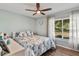 Inviting bedroom with a ceiling fan, ocean-themed bedding, and a window with a picturesque outdoor view at 38314 Echols Rd, Leesburg, FL 34788