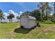 Backyard storage shed near the lake with an expansive lawn and tropical landscaping at 38314 Echols Rd, Leesburg, FL 34788