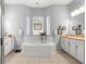 Bright bathroom featuring a large soaking tub surrounded by windows, white cabinets, and tile floors at 39145 Treeline Dr, Lady Lake, FL 32159