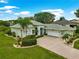 Well-manicured home with a three-car garage and brick-paved driveway, complemented by lush tropical landscaping at 39145 Treeline Dr, Lady Lake, FL 32159