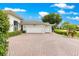 Multi-car garage and meticulously designed brick driveway, framed by verdant shrubs and swaying palm trees at 39145 Treeline Dr, Lady Lake, FL 32159