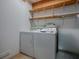 This is a laundry room with a washer and dryer with wooden shelves above at 409 Westwood Dr, Leesburg, FL 34748