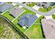 Aerial view of a home with a dark roof surrounded by green lawns, a fence, and neighboring properties at 4157 Tiedemann Loop, The Villages, FL 32163