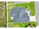 Aerial view of a home with a dark roof, well-maintained lawn and surrounded by a fence and green space at 4157 Tiedemann Loop, The Villages, FL 32163