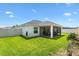 Spacious backyard featuring lush lawn, a screened patio, and privacy fencing at 4157 Tiedemann Loop, The Villages, FL 32163