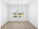 Dining room with modern chandelier, large window, and luxury vinyl plank flooring at 4157 Tiedemann Loop, The Villages, FL 32163