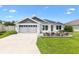 Charming single-story home with a well-manicured lawn and a gray two-car garage, perfect for suburban living at 4157 Tiedemann Loop, The Villages, FL 32163