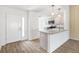 Bright kitchen featuring granite countertops, stainless steel appliances, and light wood flooring that leads to the front door at 4157 Tiedemann Loop, The Villages, FL 32163