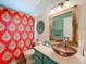 Stylish bathroom with a glass sink, decorative mirror, and vibrant shower curtain at 4800 Tara View Rd, Leesburg, FL 34748