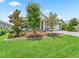 Front yard featuring mature trees, plants, mulch beds, and well-maintained lawn creating a picturesque landscape at 5019 Ne 125Th Loop, Oxford, FL 34484