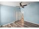 Bedroom with wood-look floors, a ceiling fan, and a view of the closet with double doors at 5068 Ne 121St Ave, Oxford, FL 34484