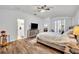 Main bedroom with wood-look floors, ceiling fan, and access to ensuite bathroom and porch at 5964 Brittania Blvd, Tavares, FL 32778