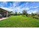 Expansive backyard with lush green lawn, mature trees, and peaceful pond views at 6008 Apex Way, Lady Lake, FL 32159