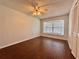 Neutral bedroom showcasing a ceiling fan, wood floors, and a window with a view to the outside at 604 Ponderosa Dr, St Cloud, FL 34769