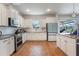 Well-lit kitchen with stainless appliances, white cabinets, wood-look floors, and access to the lanai at 637 Neptune Dr, Groveland, FL 34736