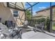 Cozy screened-in patio with stone fire pit, chairs, and view of private backyard at 637 Neptune Dr, Groveland, FL 34736