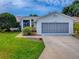 Charming home featuring a well-manicured lawn, landscaping, and a screened two-car garage at 712 Old Oaks Ln, Leesburg, FL 34748