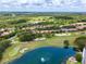 An aerial view of a neighborhood showcasing beautiful homes with red tile roofs surrounding a lush golf course and pond at 9335 San Jose Blvd, Howey In The Hills, FL 34737