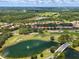 An aerial view of a neighborhood showcasing beautiful homes with red tile roofs surrounding a lush golf course and pond at 9335 San Jose Blvd, Howey In The Hills, FL 34737