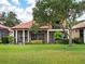 Home exterior displaying a lush green lawn, mature trees, and a screened patio at 9335 San Jose Blvd, Howey In The Hills, FL 34737