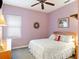 Cozy bedroom with lilac walls, a ceiling fan, and a soft, patterned comforter at 9335 San Jose Blvd, Howey In The Hills, FL 34737
