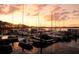 Beautiful sunset view of a boat dock with various boats and their reflections on the water at 9335 San Jose Blvd, Howey In The Hills, FL 34737