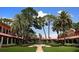 Lush courtyard with a fountain and covered walkway, surrounded by manicured lawns and palm trees at 9335 San Jose Blvd, Howey In The Hills, FL 34737