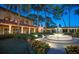 Elegant building with a fountain, manicured lawns, and lush landscaping at dusk at 9335 San Jose Blvd, Howey In The Hills, FL 34737