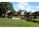Picturesque view of an expansive building on a golf course with a tranquil pond and meticulous landscaping at 9335 San Jose Blvd, Howey In The Hills, FL 34737