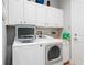 Well-organized laundry room featuring modern, white front-loading washer and dryer with counter space at 9335 San Jose Blvd, Howey In The Hills, FL 34737