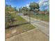 View of home with long driveway and gated yard, enhanced by mature trees and flowering bushes at 100 W Idlewild Ave, Eustis, FL 32726