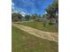 View of home with grassy front yard and sidewalk, accented by mature trees and flowering bushes at 100 W Idlewild Ave, Eustis, FL 32726