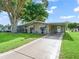 Single-story home with a long driveway, covered carport, and neatly maintained lawn, showcasing curb appeal at 1005 Richard Dr, The Villages, FL 32159