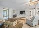 Cozy living room featuring light wood floors, ceiling fan, entertainment center and a large sliding glass door at 1005 Richard Dr, The Villages, FL 32159