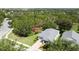 Aerial view of a gray home with a brick driveway surrounded by mature trees and green lawns at 101 Flame Vine Way, Groveland, FL 34736