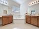 Bathroom with a soaking tub surrounded by tile and separate vanities with dual sinks at 101 Flame Vine Way, Groveland, FL 34736