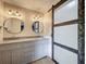 Bathroom vanity featuring double sinks, granite countertop, round mirrors, wood flooring and a sliding door at 1156 Capella Dr, Tavares, FL 32778