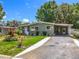 Charming single-story home with a well-maintained lawn, colorful flowers, and a concrete driveway leading to a covered carport at 1156 Capella Dr, Tavares, FL 32778