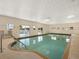 Bright indoor pool with a stepped entry, handrails, and multiple windows at 1156 Capella Dr, Tavares, FL 32778