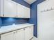 Bright mudroom with white cabinets, quartz countertops and contrasting blue wall paint at 1156 Capella Dr, Tavares, FL 32778