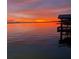 Gorgeous sunset reflecting on the lake, featuring a dock and vibrant hues in the sky at 1156 Capella Dr, Tavares, FL 32778