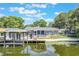 Waterfront property features a dock, screened porch, and backyard with lush landscaping at 11750 Watts Ct, Tavares, FL 32778