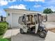 Golf cart parked in front of a garage with a picket fence and landscaping at 1199 Mathews Ln, The Villages, FL 32162