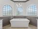 Bright bathroom featuring a modern freestanding tub beneath three arched windows at 12198 Se 176Th Loop, Summerfield, FL 34491