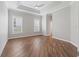 Spacious bedroom with tray ceiling, two windows, and wood flooring at 12198 Se 176Th Loop, Summerfield, FL 34491