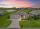 Beautiful single-story home featuring a manicured lawn and a picturesque view of a golf course at sunset at 12198 Se 176Th Loop, Summerfield, FL 34491