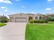 Front exterior view of the home featuring mature trees, a long driveway, and well-manicured landscaping at 12198 Se 176Th Loop, Summerfield, FL 34491