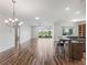 Spacious living room with wood-look floors, modern light fixture, and view to the outdoor space at 12198 Se 176Th Loop, Summerfield, FL 34491