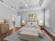 Stylishly furnished main bedroom boasts tray ceiling, bright window, and wood flooring at 12198 Se 176Th Loop, Summerfield, FL 34491