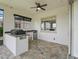 Inviting outdoor kitchen featuring a built-in grill, mini fridge, sink, and stylish brick flooring under a ceiling fan at 12198 Se 176Th Loop, Summerfield, FL 34491